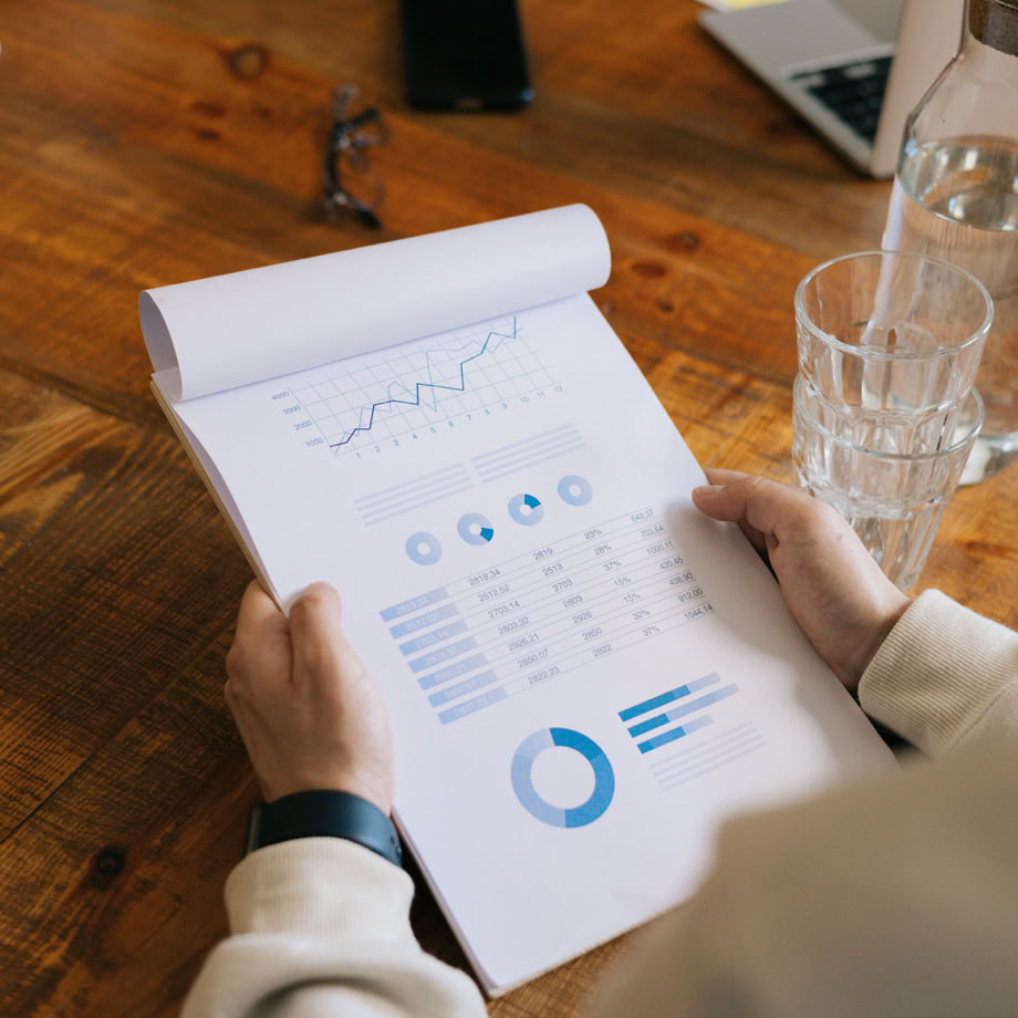 Close-up of hands holding a document with graphs and charts during a business meeting.